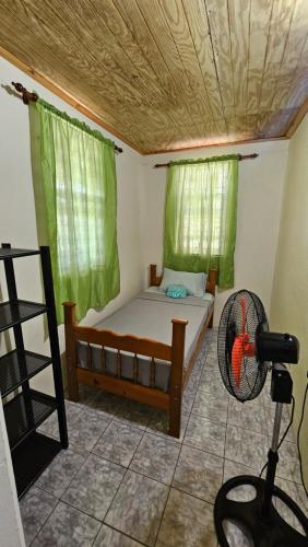 a small bedroom with a bed and a fan at Hidden Bungalow in Roseau