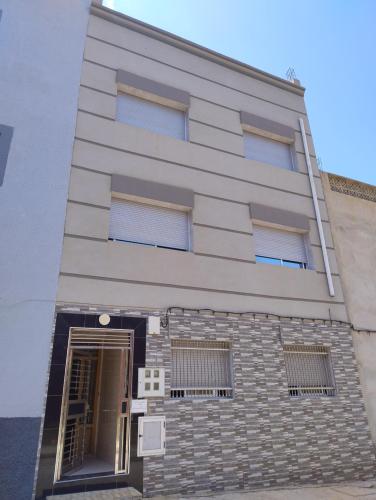 a tall white building with windows and a door at Centre boukidan in Al Hoceïma