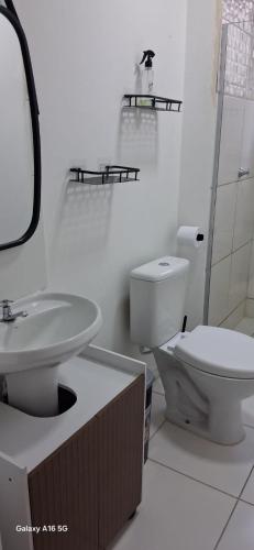 a white bathroom with a toilet and a sink at Townhouse Flat Térreo in Ananindeua