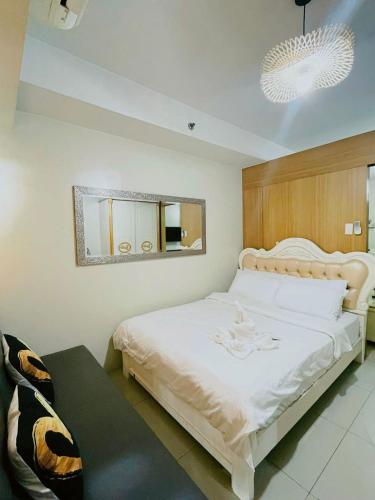 a bedroom with a large white bed with a mirror at Shell Residences MOA - Josh staycation in Manila