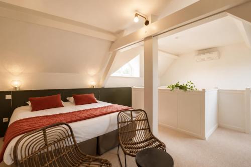 a bedroom with a large bed and two chairs at Ermitage De Corton - Teritoria in Chorey-lès-Beaune