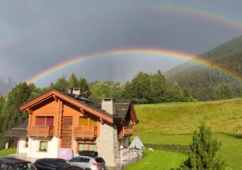 a rainbow in the sky over a house at Chalet Taulei tra Bormio e Livigno in Valdidentro