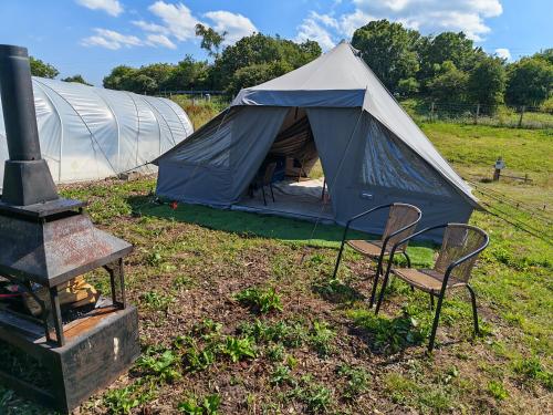 a blue and white tent with two chairs and a stove at Gallow Hill Campsite in Startforth