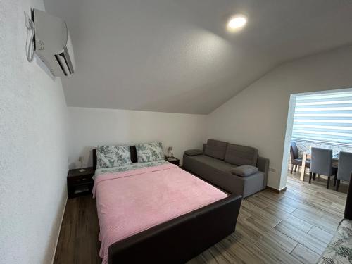 a bedroom with a bed and a couch and a window at Irena Apartment near Aqua Park in Trebinje