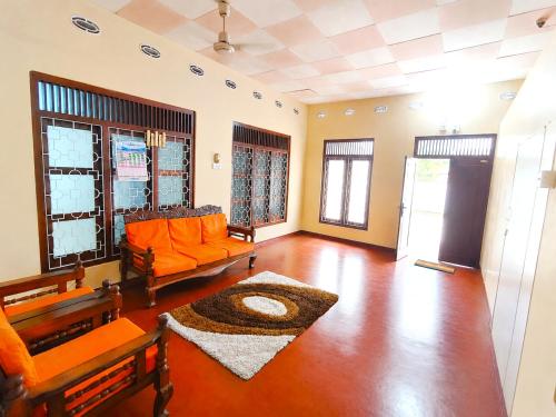 a living room with an orange couch and a rug at Yarl Retreat Villa - Non-AC in Jaffna