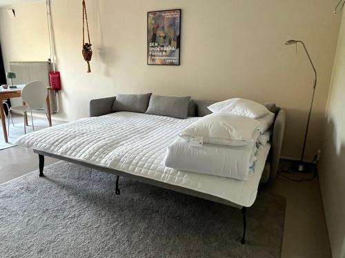 a bed with white sheets and pillows in a room at Sommarboende i centrala Varberg in Varberg