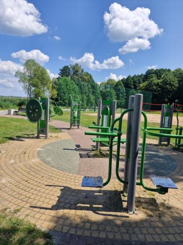 a park with green benches and a playground at Apartament BLASK Jeziora in Augustów