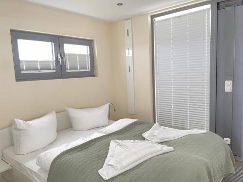a bedroom with a bed with white pillows and a window at Hausboot Paula mit Reisekajak in Ribnitz-Damgarten in Ribnitz-Damgarten