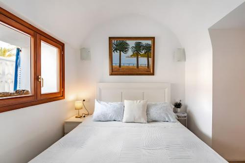 a bedroom with a white bed with a picture on the wall at Molino Son Moll in Cala Ratjada