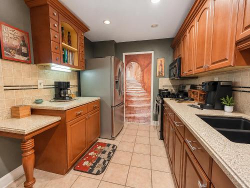 a kitchen with wooden cabinets and a stainless steel refrigerator at Lovely 2BR Condo WFH Heart of Downtown Pool Access in Atlanta