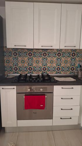 a kitchen with white cabinets and a stove with a red towel at guesthouseminturnoit Lucia Sparagna in Minturno