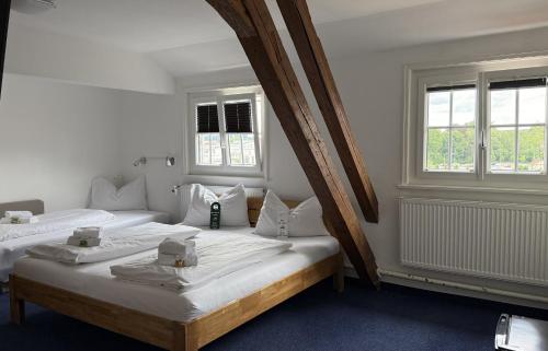 two beds in a white room with two windows at Hotel Hasen Kaufbeuren Allgäu in Kaufbeuren