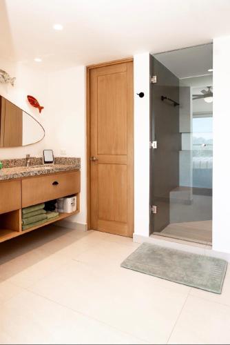 a bathroom with a shower and a wooden door at Sunset view Penthouse 302 in Cabo San Lucas