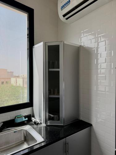 a white kitchen with a sink and a window at Luxury Cozy 2BR Penthouse in Ḩayl Āl ‘Umayr