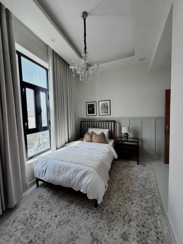 a bedroom with a large bed and a chandelier at Luxury Cozy 2BR Penthouse in Ḩayl Āl ‘Umayr