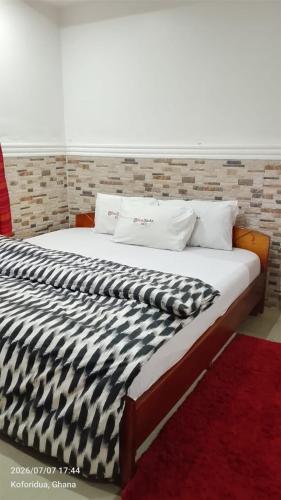 a large bed with a black and white comforter at FREDJACKSAIR BnB in Koforidua