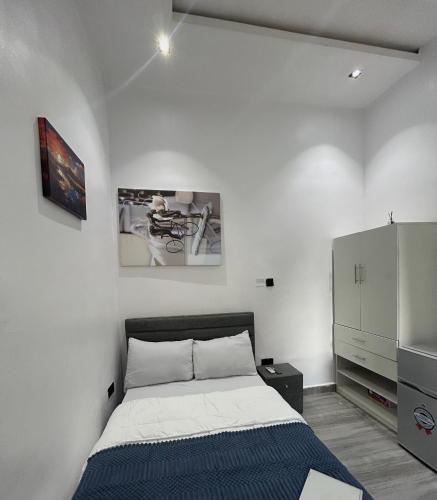 a white bedroom with a bed and a cabinet at Tameeza stays in Sangotedo