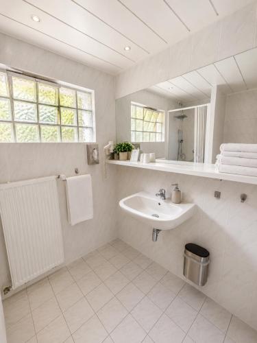 a white bathroom with a sink and a mirror at Hotel Mainbrücke in Kitzingen
