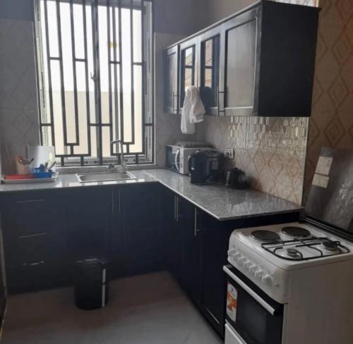 a kitchen with black cabinets and a stove and a window at Migzhome in Dodoma