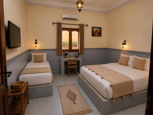 a bedroom with two beds and a television in it at Hotel la renaissance tata in Tatta