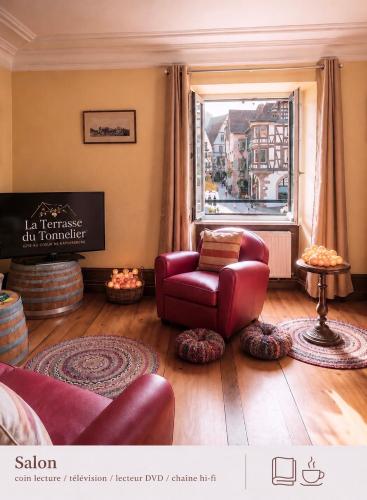 a living room with a red chair and a window at La Terrasse du Tonnelier - 92m2 - plein centre médiéval - sauna - terrasse 20m2 - garage in Kaysersberg