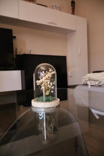a glass dome with a vase of flowers on a table at Central apartments Pleven in Pleven
