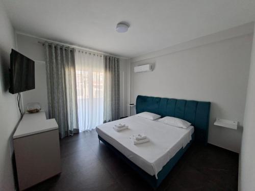 a bedroom with a bed with a blue headboard and a television at TRIUMPH rooms and apartment in Vlorë