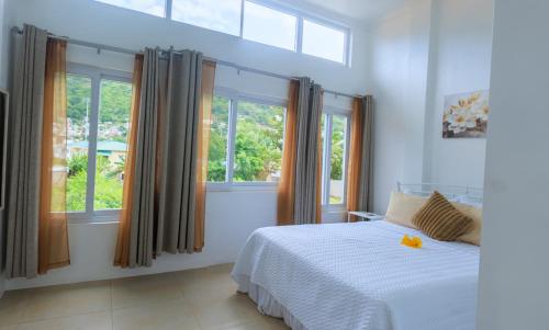 a bedroom with a bed and two windows at Agape Suites-Room 3- 1st Floor in Soufrière