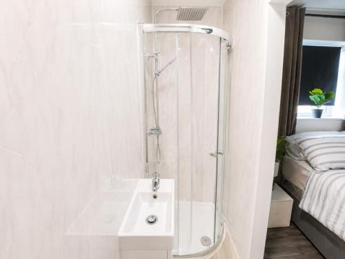 a white bathroom with a shower and a sink at UNLIMITED-PEACE PRIVATE STUDIO APARTMENTs in Weston-super-Mare