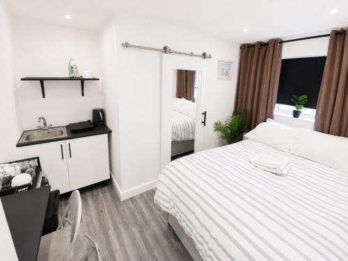 a white bedroom with a bed and a sink at UNLIMITED-PEACE PRIVATE STUDIO APARTMENTs in Weston-super-Mare