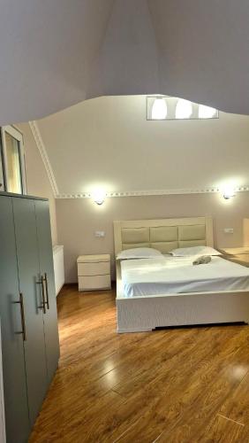 a bedroom with a white bed and wooden floors at Busheti Home in Telavi