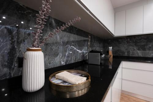 a black kitchen with a white vase with flowers in it at Villa Machim - Heated Pool - View in Machico