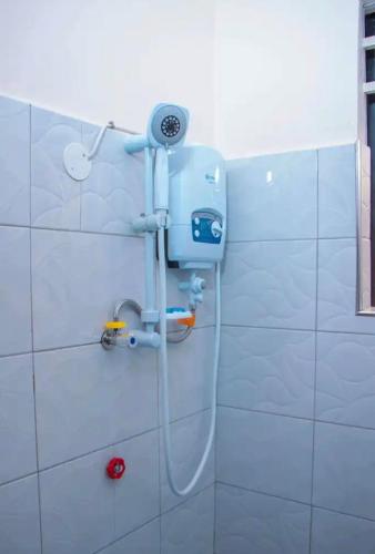 a shower in a white tiled bathroom with a shower at Gugga Suites Mbale in Mbale