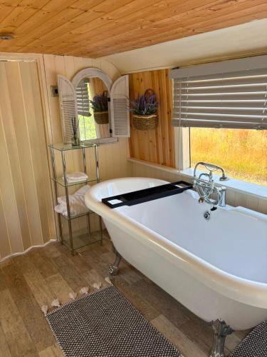 a white tub in a room with a window at Debdale Bus Retreat in Little Dalby