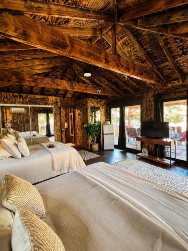two beds in a room with wooden ceilings at JAWS Retreat Bungalow in Haleiwa