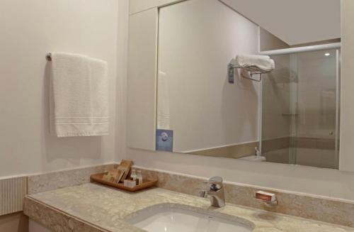 a bathroom with a sink and a mirror at Flat em Alphaville Hotel Comfort in Barueri