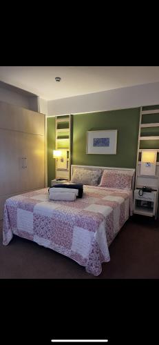 a bedroom with two beds and a green wall at Flat em Alphaville Hotel Comfort in Barueri