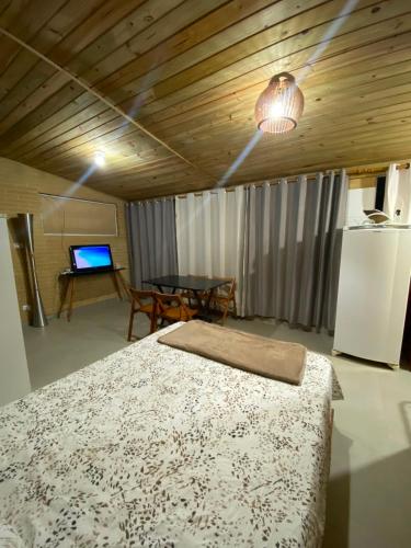 a bedroom with a bed and a table and a refrigerator at Chalés Mar & Mata Paraty in Paraty