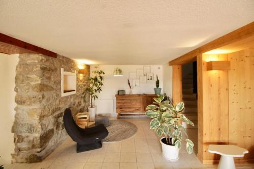 a living room with a black chair and a stone wall at Lodge Les Cariolettes in Font-Romeu-Odeillo-Via