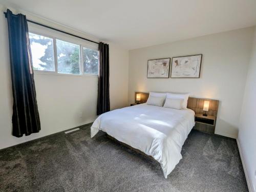 a bedroom with a large white bed and a window at Mountview Maison in Red Deer