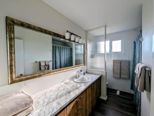 a bathroom with a sink and a large mirror at Mountview Maison in Red Deer