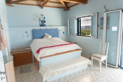 a bedroom with a bed and a chair in it at Villa Azul - A Timeless Retreat Above the Aegean in Alonnisos