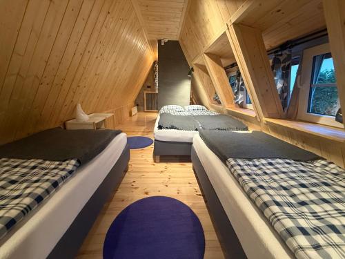 two beds in a room with wooden walls and wooden floors at Kamień na Kaszubach in Kamień