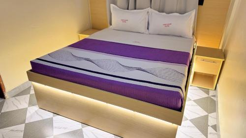 a bed with purple and white sheets on it at Kent One Hotel in Fort Portal