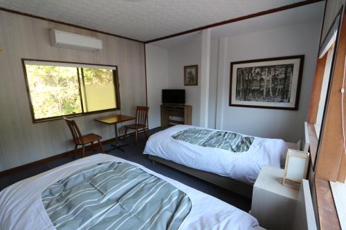 a bedroom with two beds and a desk and a window at Higashiyamaan in Takayama