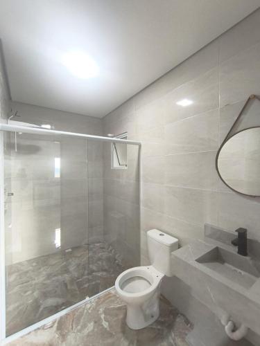 a bathroom with a white toilet and a shower at Refúgio dos ventos in Campos do Jordão