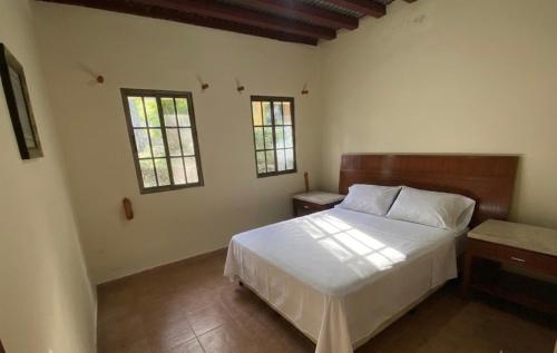 a bedroom with a white bed and two windows at The Mexican in Los Altos de Cerro Azul