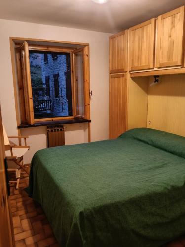 a bedroom with a green bed and a window at Il gallo alpino a Champorcher in Champorcher