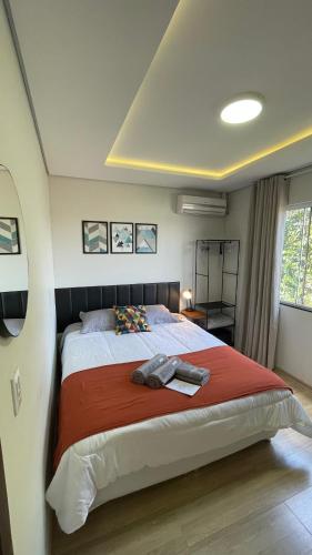 a bedroom with a large bed with a red blanket at Villa Serena Garden - Quarto Cama Queen - Banheiro Compartilhado in Cascavel