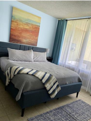 a bedroom with a bed with a painting on the wall at Carey Beach Villa in Humacao